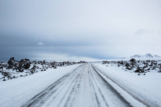 A road full of snow in winter in Iceland with mountains in the background