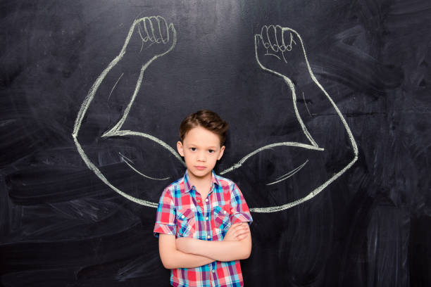 istock Powerful young schoolboy with drawn muscules on blacboard 958984406