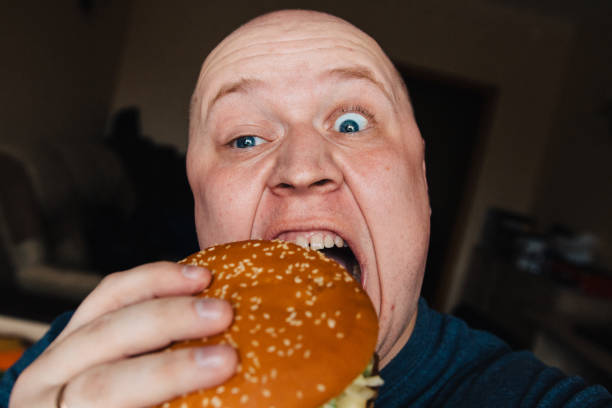 istock The eating of a hamburger by a man with a terrible expression 958987972