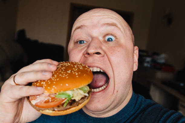 istock The eating of a hamburger by a man with a terrible expression 958988016