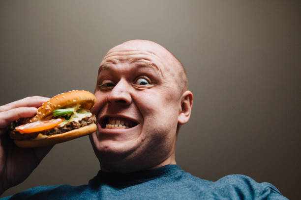 istock The eating of a hamburger by a man with a terrible expression 958988242