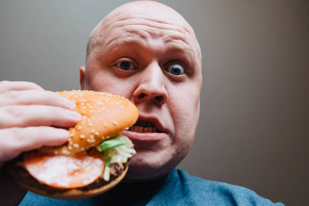 istock The eating of a hamburger by a man with a terrible expression 958988326