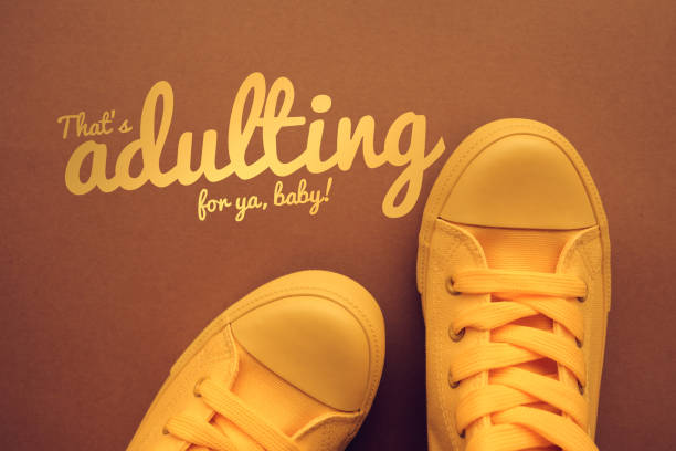 Words and phrases millennials use, conceptual image with young person in yellow sneakers standing directly above text - That's adulting for ya, baby