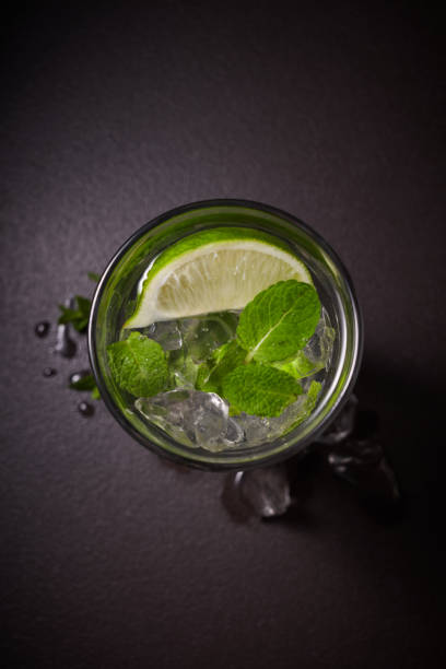 istock Tradition Summer drink mojito with lime and mint in glass on dark stone background 958989412