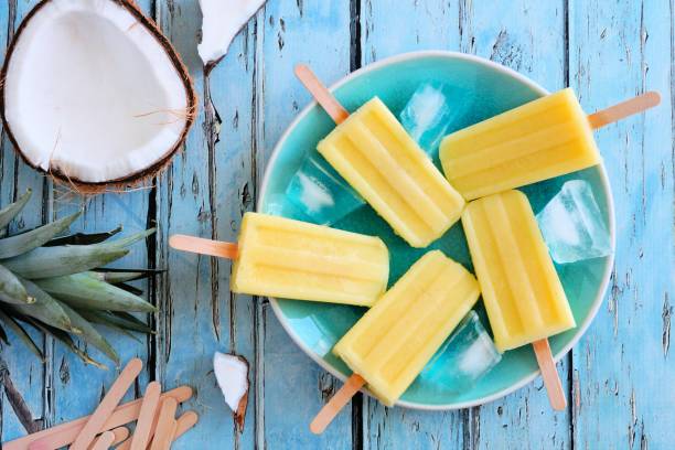 istock Pineapple coconut popsicles, top view scene on blue wood 958992630