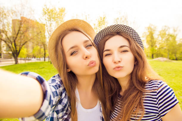 istock Two beautiful girls in caps making selfie and pouting 958992642