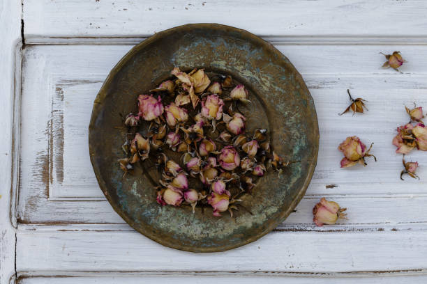 Topview of small dried pink roses on bronze vintage plate over white rustic backround