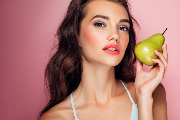 Beautiful girl holding a juicy pear Beautiful girl holding a juicy pear perfect pear stock pictures, royalty-free photos & images