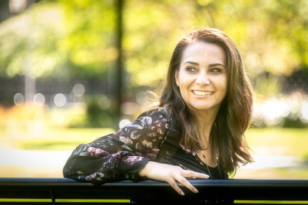 istock Smiling woman sitting in a bench looking away 959007726