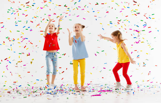 bambini felici in vacanza saltando in coriandoli multicolori su bianco - 8446 foto e immagini stock