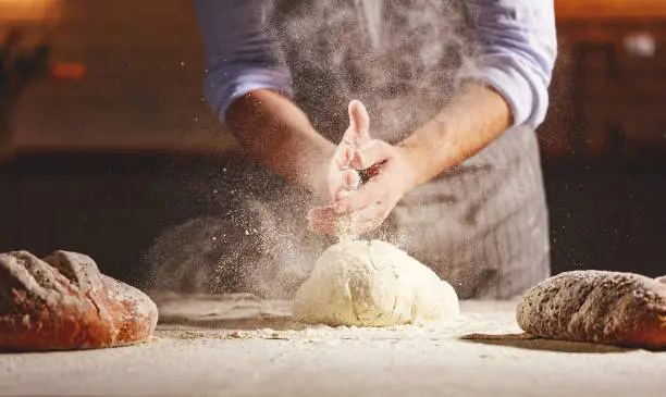hands of the baker's male knead dough