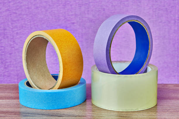 istock Four rolls of adhesive tape lying on table, lilac background. 959014020