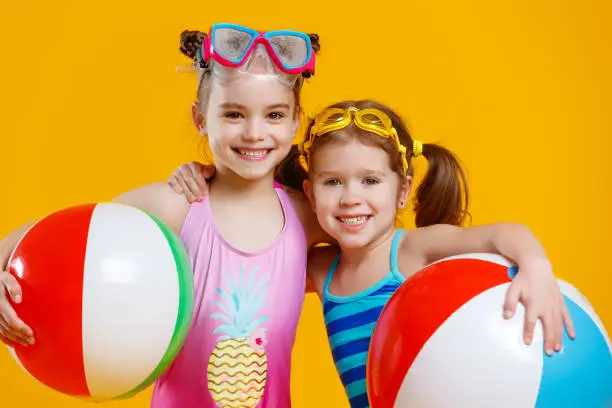 Photo of funny funny happy children in bathing suits and swimming glasses on colored background