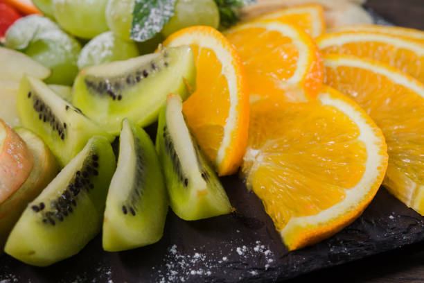 istock Fruit slicing on a wooden background and on a stone stand 959016410