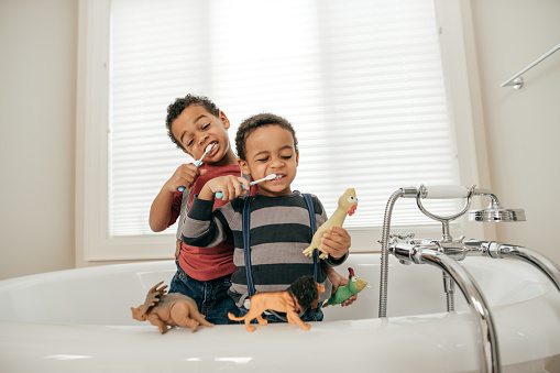 Two boys brushing their teeth at the bathroom.