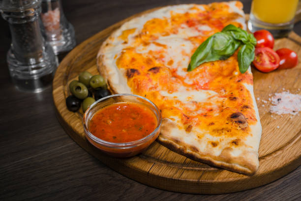 istock Hot piece of pizza with melted cheese on a rustic wooden table 959027274