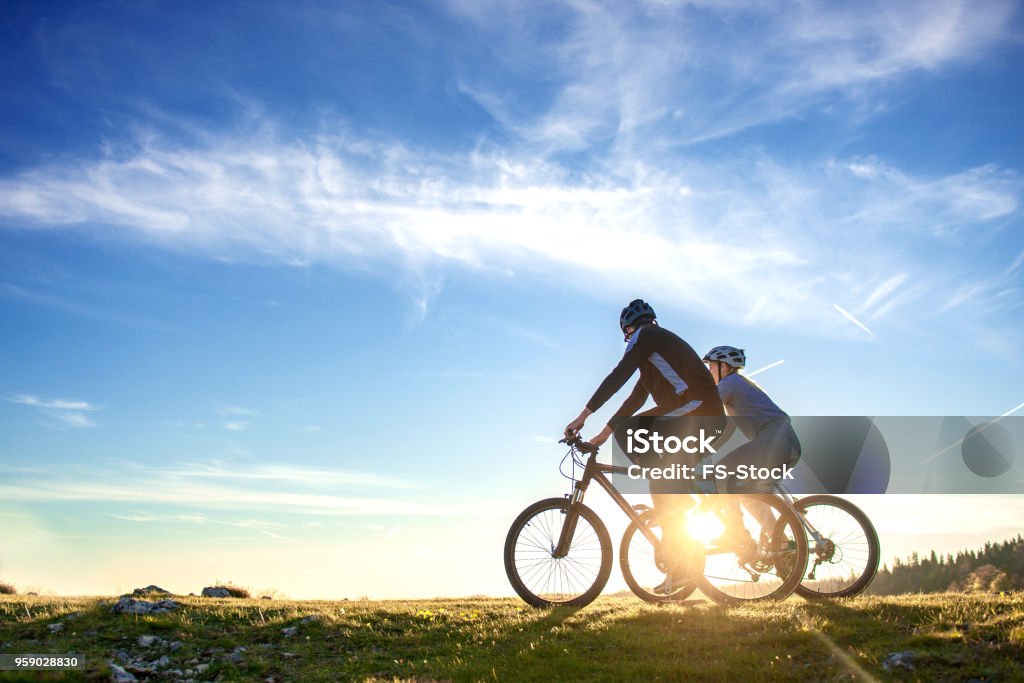 Par De Bicicletas De Montaña Feliz Al Aire Divertirse Juntos En Un Puesta De Sol Por La Tarde De Verano Foto de stock y más banco de de Andar en