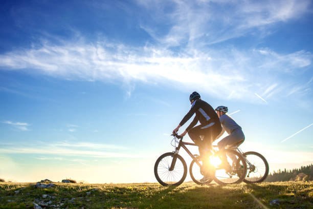 Happy mountain bike couple outdoors have fun together on a summer afternoon sunset Happy mountain bike couple outdoors have fun together on a summer afternoon sunset. adults exercising stock pictures, royalty-free photos & images
