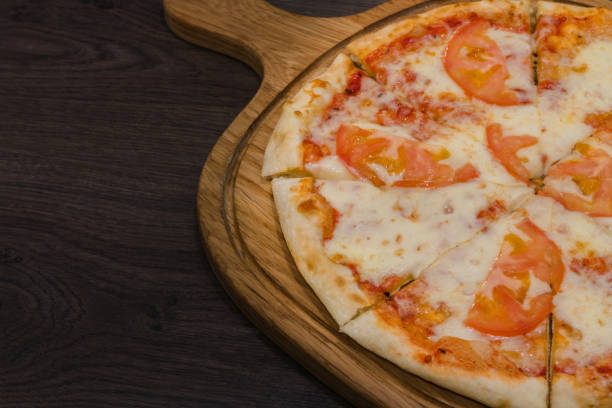 istock Hot piece of pizza with melted cheese on a rustic wooden table 959035182
