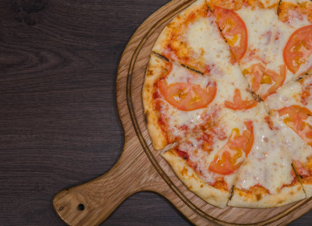 istock Hot piece of pizza with melted cheese on a rustic wooden table 959035444