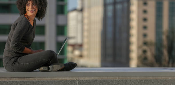 Woman working on laptop atop a building