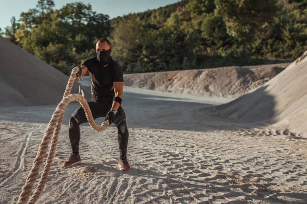 istock Young man having a sport training with ropes in the quarry 959043208