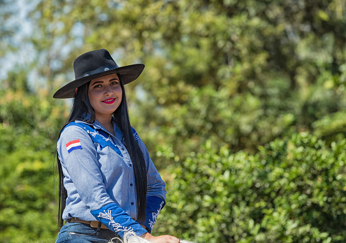 Colonia Independencia: A beautiful woman proudly rides her horse during the annual Paraguayan Independence Day parade. She wears the costume of the Gouchos the cowboys of South America.