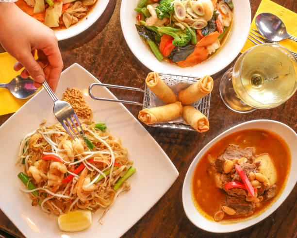 istock Overhead shot of Thai food on a table, with a hand holding a fork 959052538