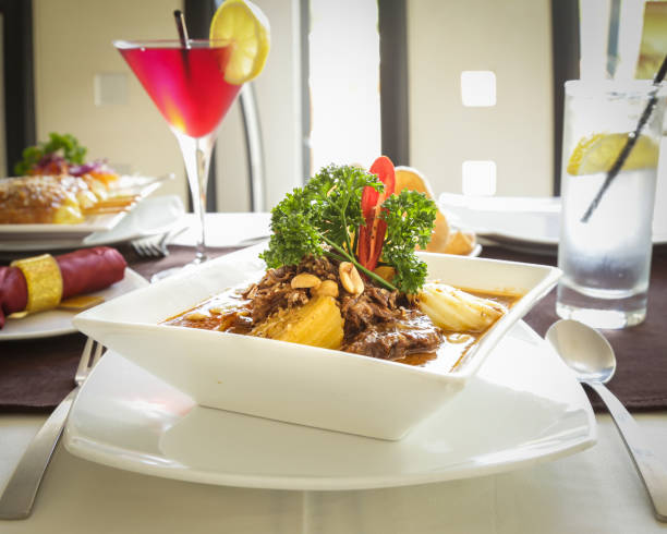 istock Thai curry with meat, vegetables and peanuts, served in square white bowl parsley garnish 959053146