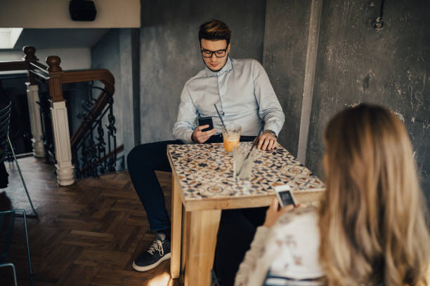 Two people using phones during a date in the coffee bar Two people using phones during a date in the coffee bar couple on bad date stock pictures, royalty-free photos & images