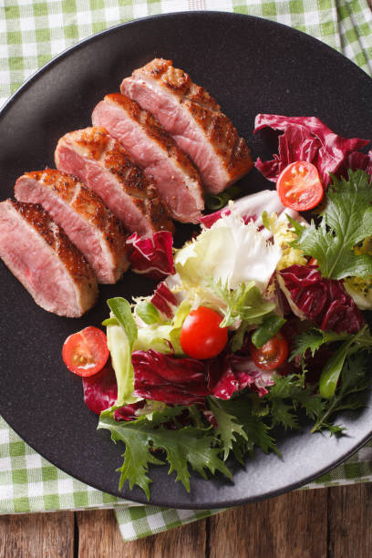 istock roast duck breast and fresh mix lettuce close-up. vertical top view 959065330
