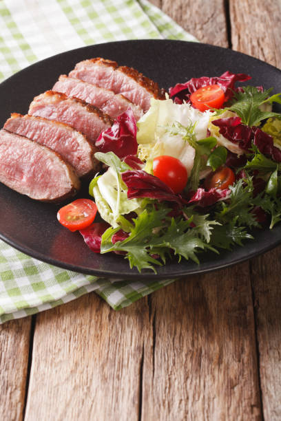istock roast duck breast and fresh mix lettuce close-up. vertical 959065360