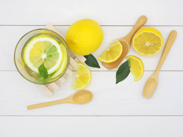 istock Fresh lemon in water and lemon slice on white wood background 959065460