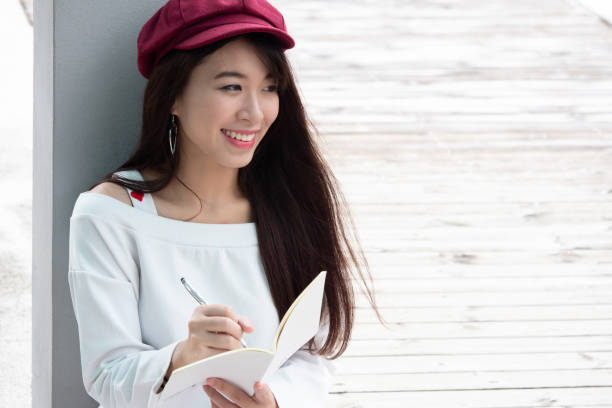 istock Young beautiful happy woman writing diary in a park 959069904