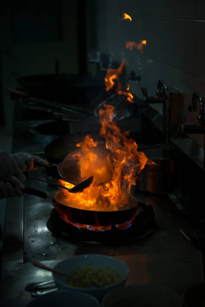 istock Chef cooking and doing flambe on food in restaurant kitchen 959075184