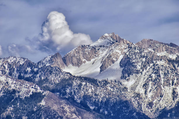 Panoramic view of Wasatch Front Rocky Mountain, highlighting Lone Peak and Thunder Mountain from the Great Salt Lake Valley in early spring with melting snow, pine trees, scrub oak and quaking aspen in Utah. stock photo