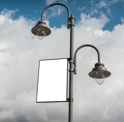 White blank rectangular billboard on a lamppost on a cloudy sky background.