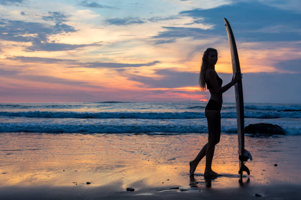 istock Sensual woman with surf board on the beach at sunset 959084144