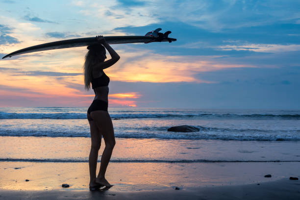 istock Sensual woman with surf board on the beach at sunset 959084572