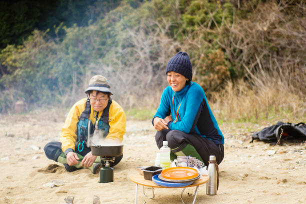 istock Two sea kayakers cooking and preparing lunch on a beach 959085420