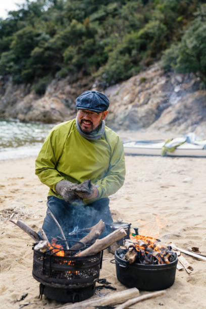 Man cooking and preparing lunch on a beach after sea kayaking