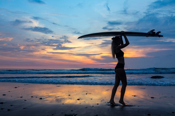 istock Sensual woman with surf board on the beach at sunset 959089924