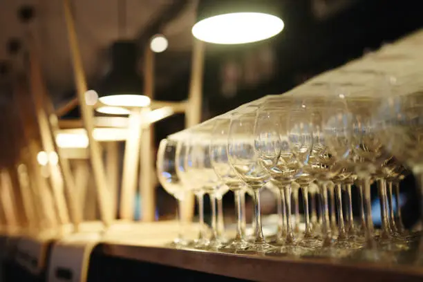 Close-up view of clean empty wine glasses and overturned stools stacked on bar counter