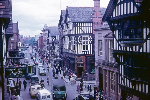 Chester, England, UK, 1960. Street scene on Bridges Street with its half-timbered houses (Rows). Furthermore: pedestrians, cars, traffic and shops.