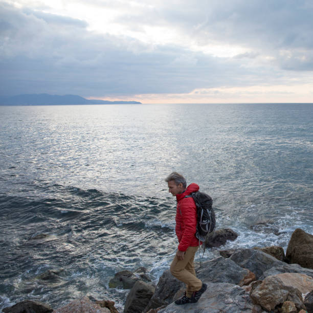 istock Mature man explores rocky shoreline and sea 959098432