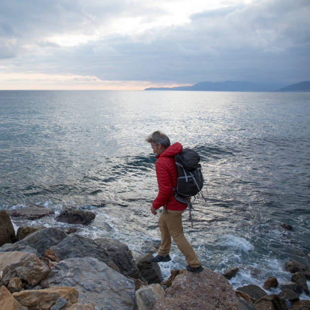 istock Mature man explores rocky shoreline and sea 959098500