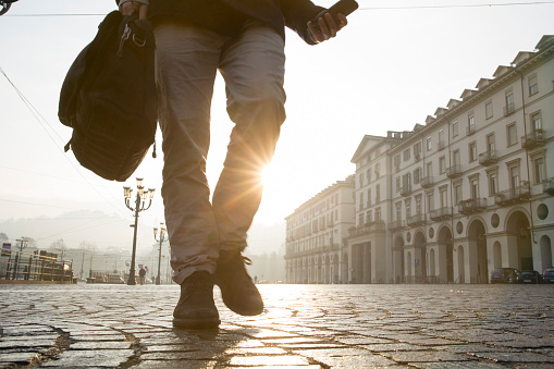 Businessman walks across cobblestones in Piazza San Vittorio, Turin