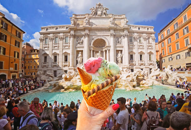 włoski lody - stożek śmietankowy trzymany w ręku na tle słynnej fontanny di trevi - trevi fountain rome fountain monument zdjęcia i obrazy z banku zdjęć