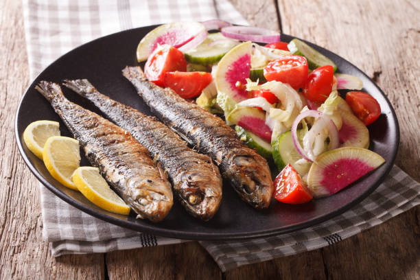 istock Mediterranean food: grilled sardines with fresh vegetable salad close-up. horizontal 959110374