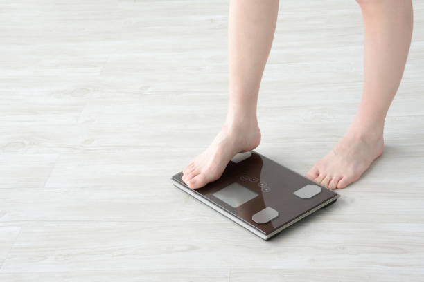 istock Woman getting on weight scale 959114308